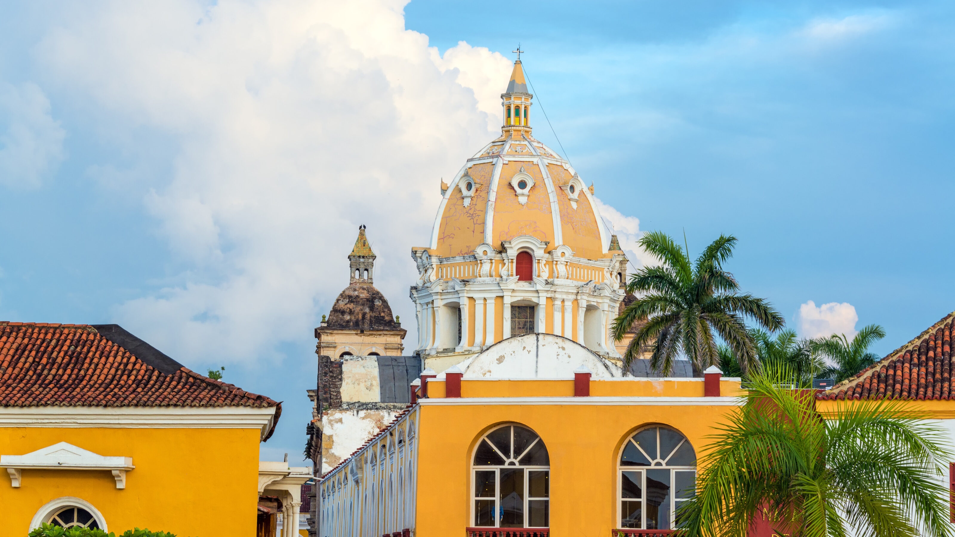 Colonial architecture with dome and palm trees against a blue sky.