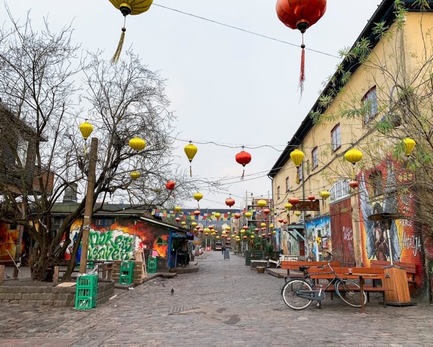 A colorful street adorned with red and yellow lanterns, graffiti walls, and empty benches.