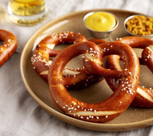 Plate with salted pretzels and mustard dips on a table.