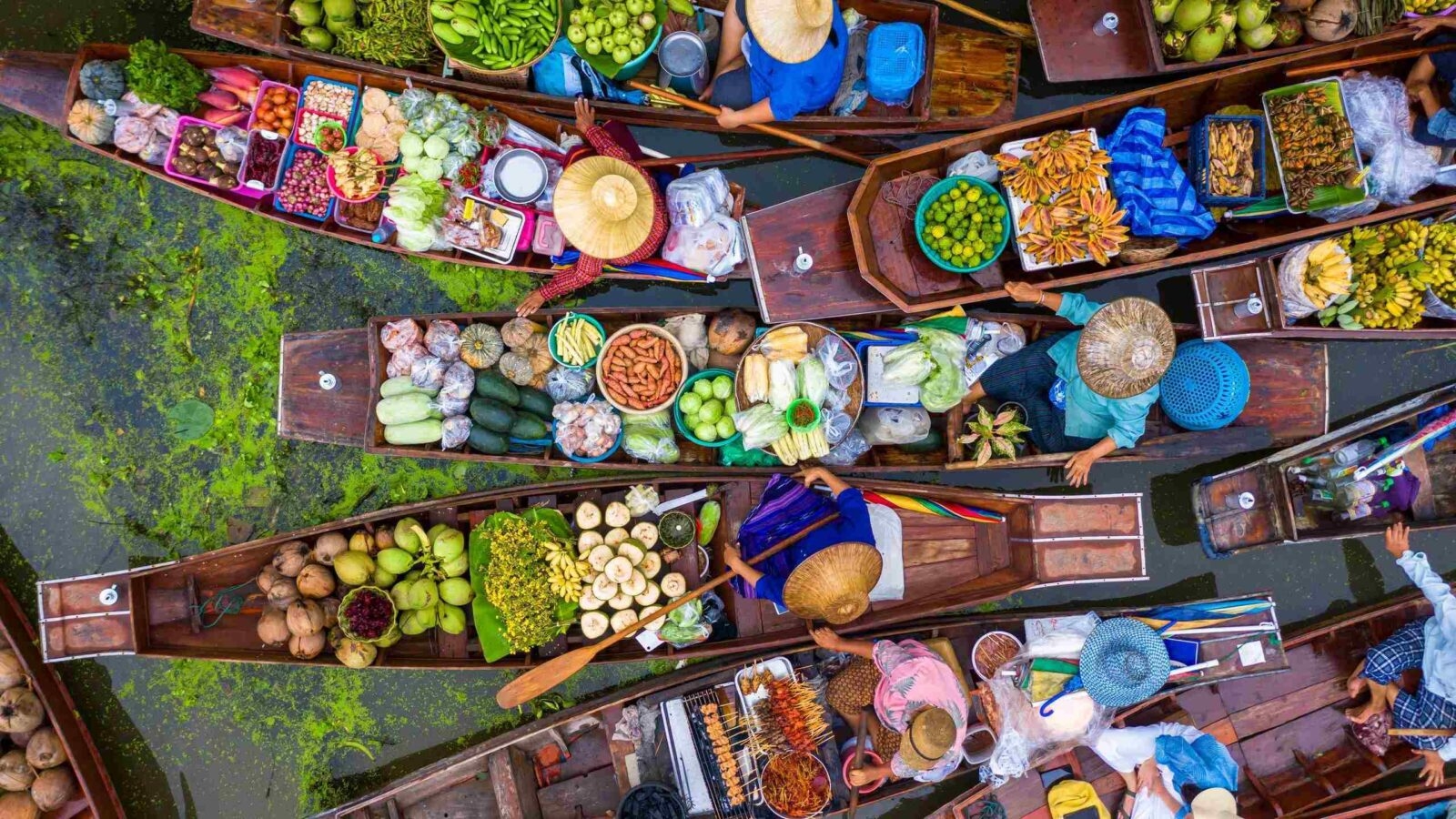 Aerial view of a vibrant floating market with vendors in boats selling fresh produce.