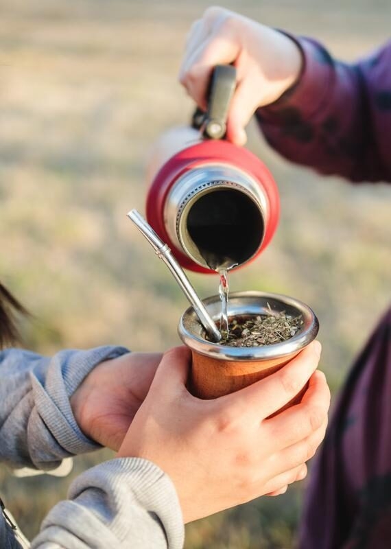 Two friends pouring a cup of mate in Argentina