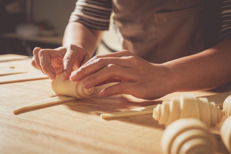 A pastry chef rolling croissants by hand