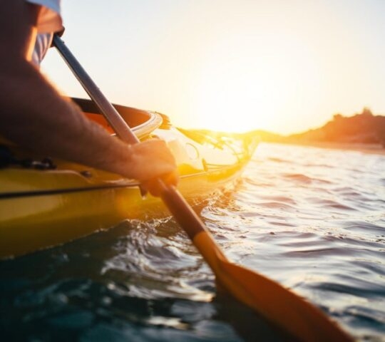 Close up of man holding kayak paddle at sunset