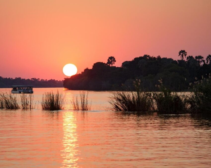 Boat cruising the Zambezi River at sunset.