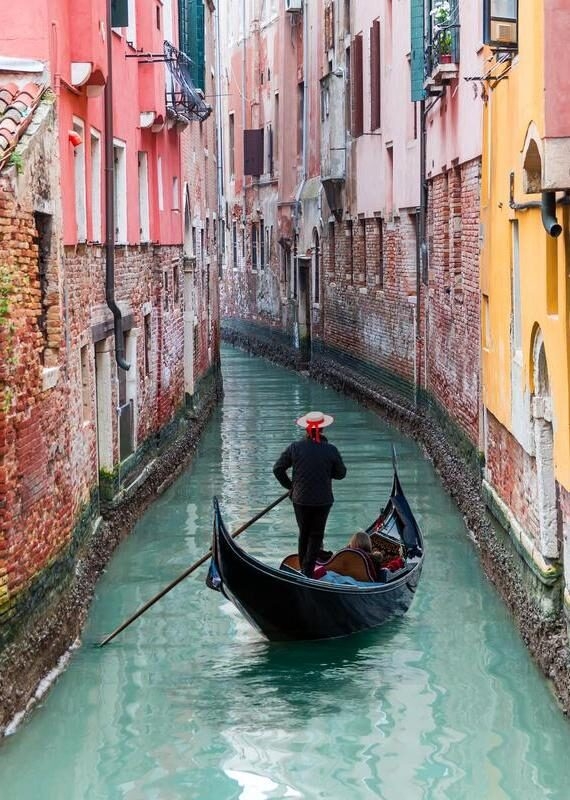 Venetian gondolier through green canal waters of Venice Italy
