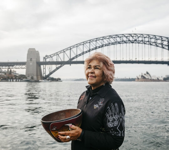 An Aboriginal guide in front of Sydney harbour bridge