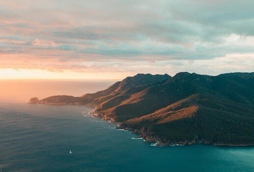 Uluru rising from the desert plains, a kangaroo wandering through vineyards in Adelaide Hills and the first light over Wineglass Bay in Tasmania’s Freycinet National Park.