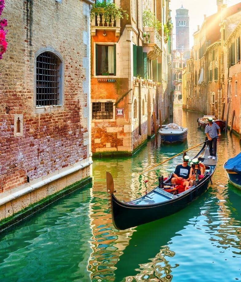 A couple enjoying a quiet gondola ride through Venice’s renowned canals and a glowing sunset over the Amalfi Coast in Positano.