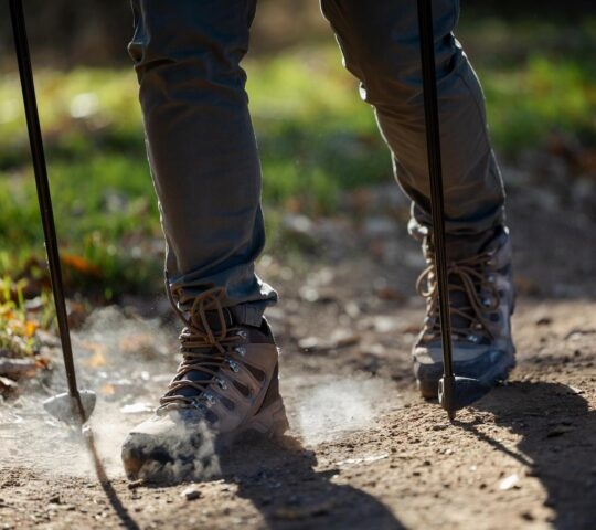 A hiker with trekking poles on a dusty trail.