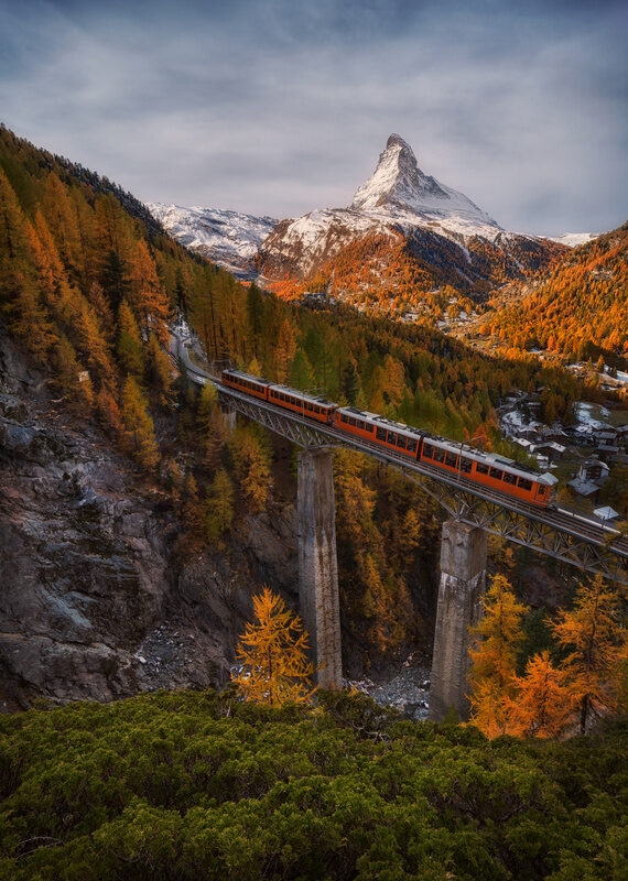 Scenic autumn view on snowy Matterhorn peak with blue cloudy sky , bridge and Gornergrat tourist train in Zermnatt, Switzerland.