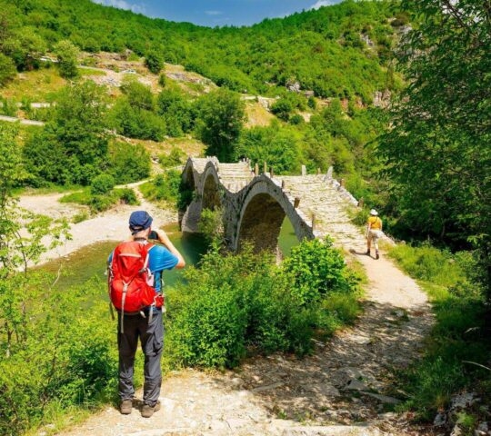 A hiker looking at a stone bridge in Zagoria, Greece