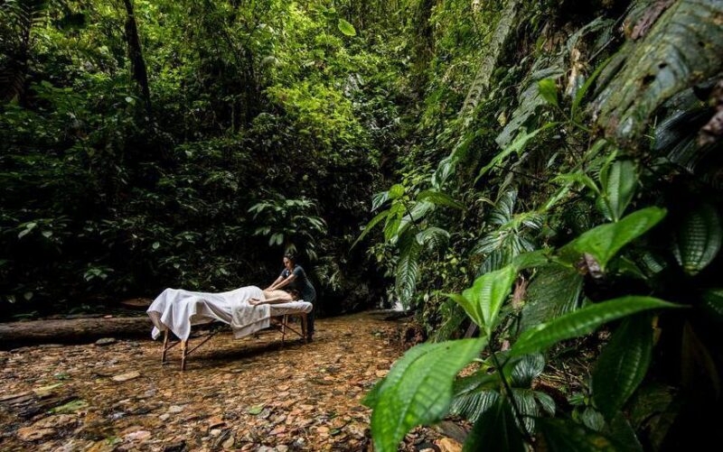 Woman receives a massage outside in the Ecuador cloud forest by a waterfall with trees all around