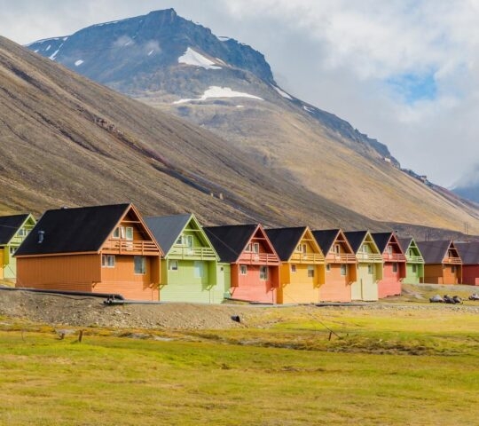 A row of colourful cabins in Longyearbyen, Svalbard set against a mountain peak.