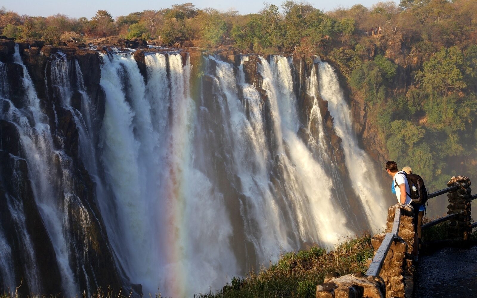 A couple taking in the sheer scale of Victoria Falls as the Zambezi River plunges into the gorge below.