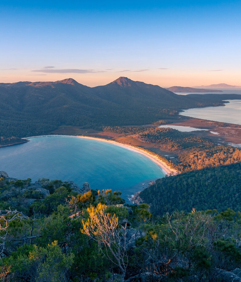 The red desert landscapes of Uluru–Kata Tjuta National Park, and the sweeping curve of white sand at Wineglass Bay in Freycinet National Park.