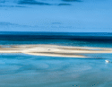Aerial view of a white sandbar and a small white boat in the turquoise waters of the Bazaruto Archipelago.