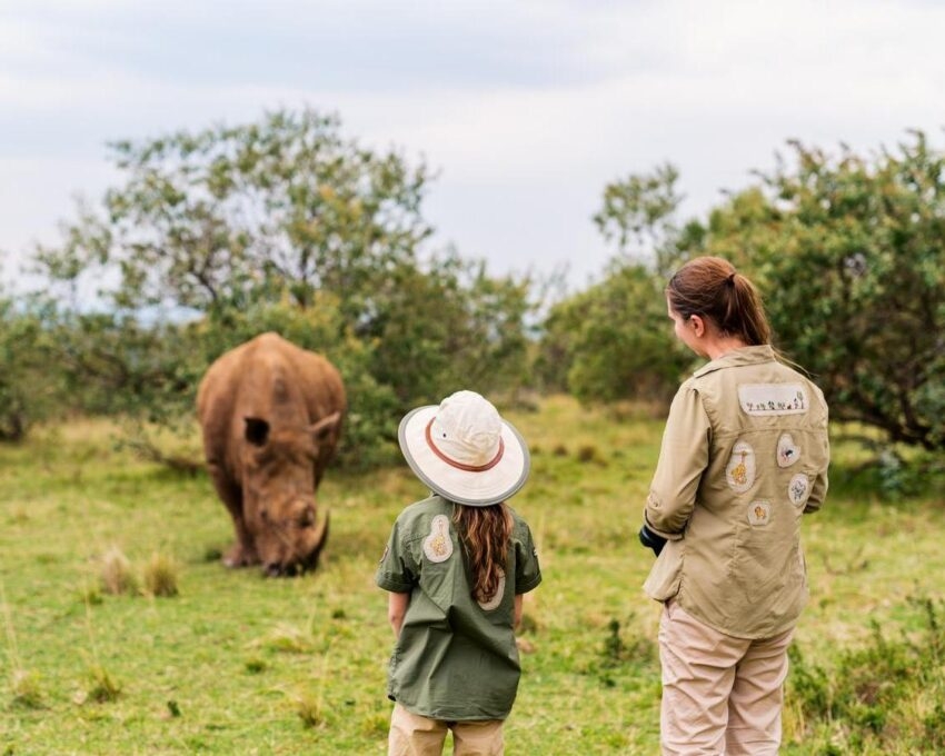 A woman and child stood watching a rhino while on a walking safari in Africa