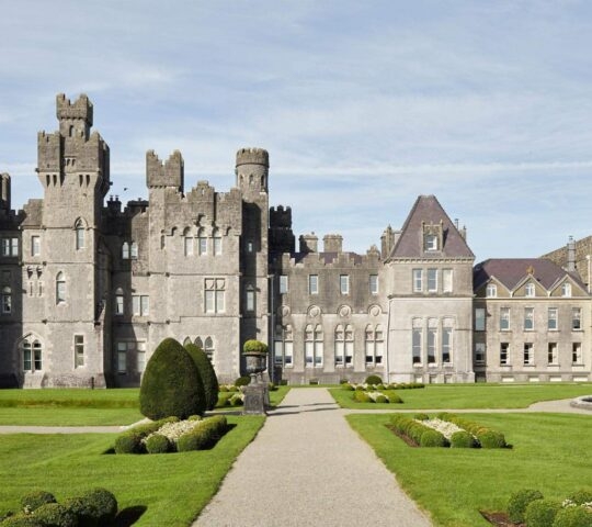 The exterior of Ashford Castle in Ireland with gardens in front