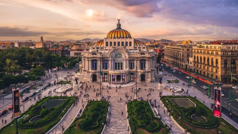 The Palacio de Bellas Artes in Mexico City at sunset with surrounding gardens.