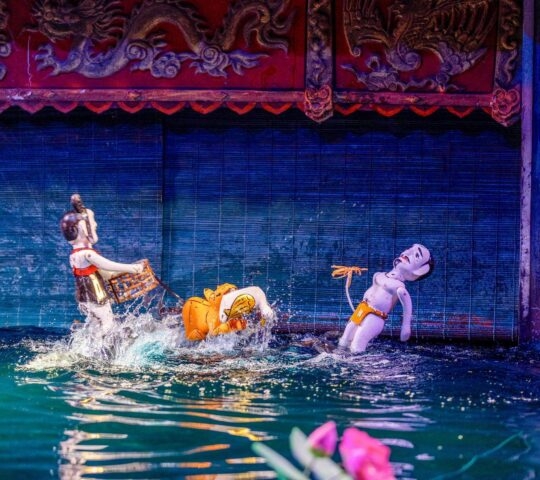 Traditional Vietnamese water puppets depicting a scene with a tiger and a person on a dark water stage.