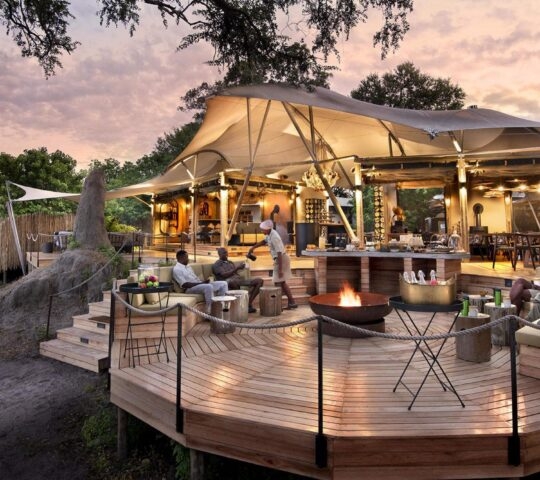 Outdoor seating area with firepit and open-sided tented camp at Khwai Leadwood in Botswana