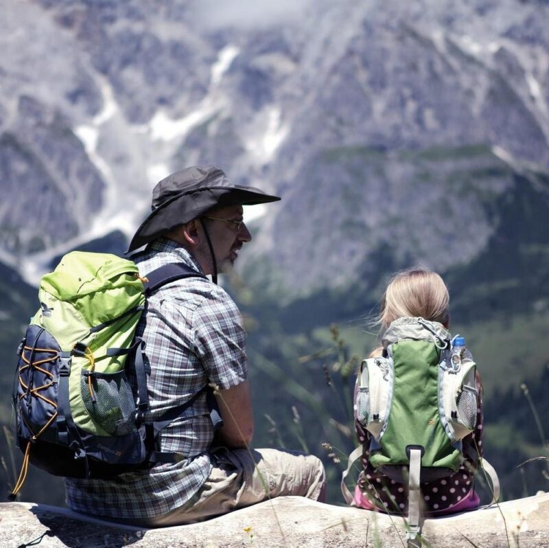 A father and daughter sat admiring the view of the Alps on a hike