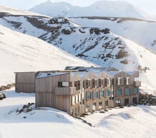 An exterior wide view of Highland Base during winter with snowy mountains in the background.