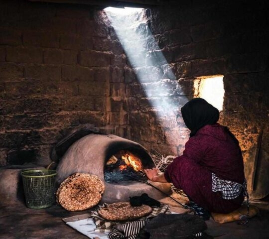 A Berber woman making bread in a traditional oven in Morocco
