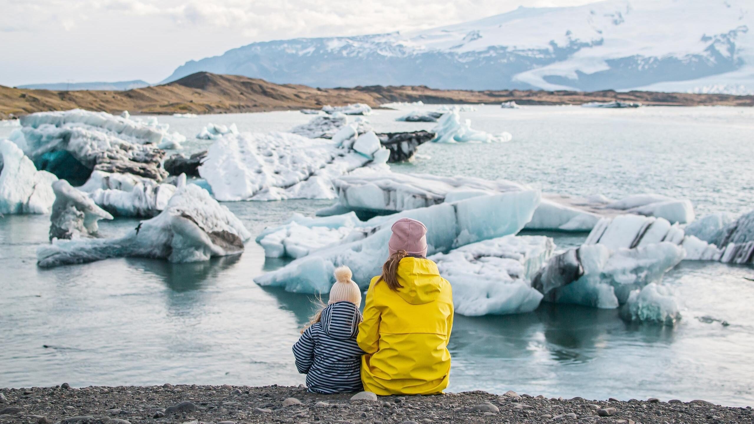 A mother and child sat side by side looking at a glacier in Iceland