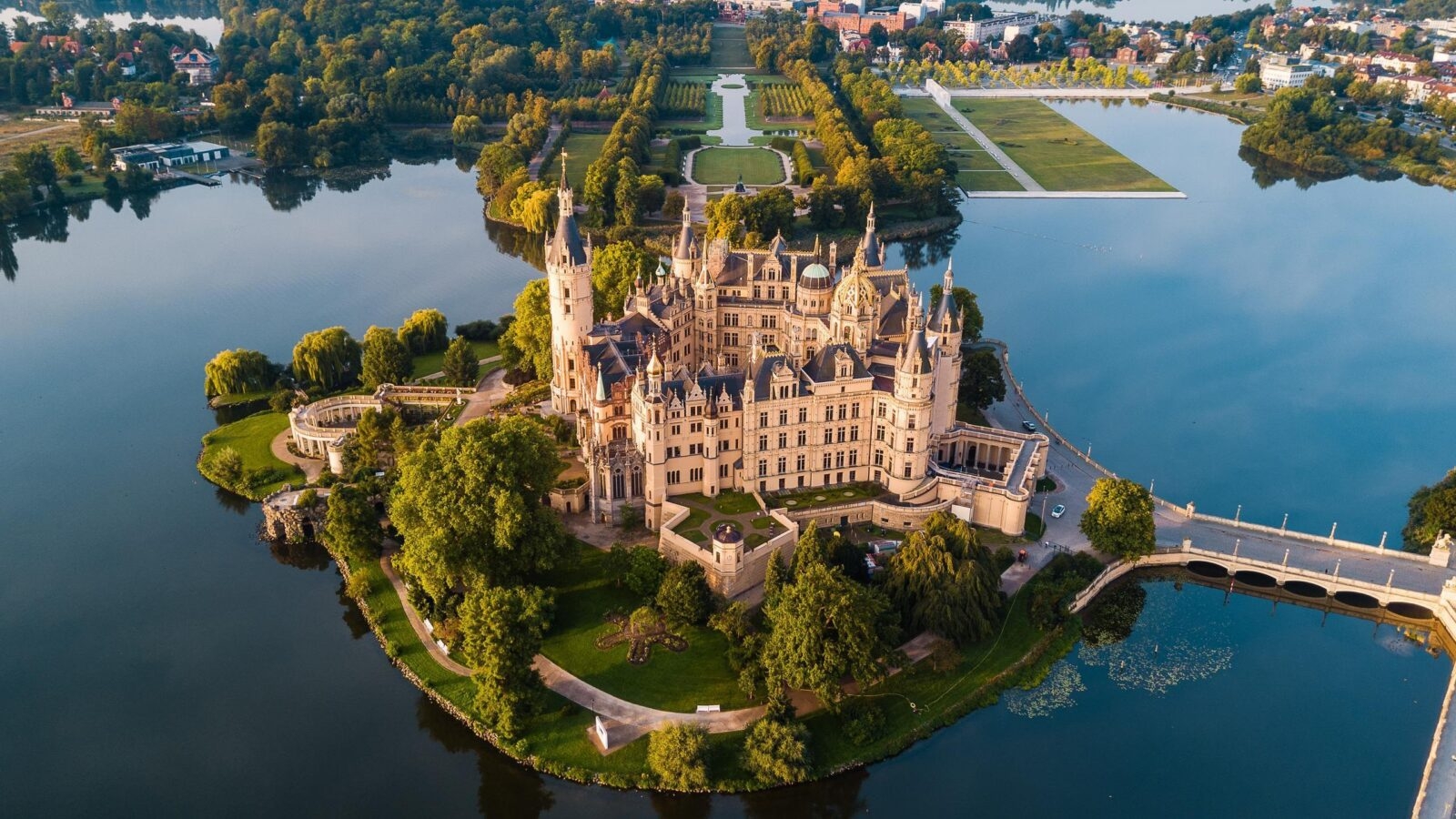 Aerial view of Schwerin Castle on an island surrounded by water and lush green gardens.