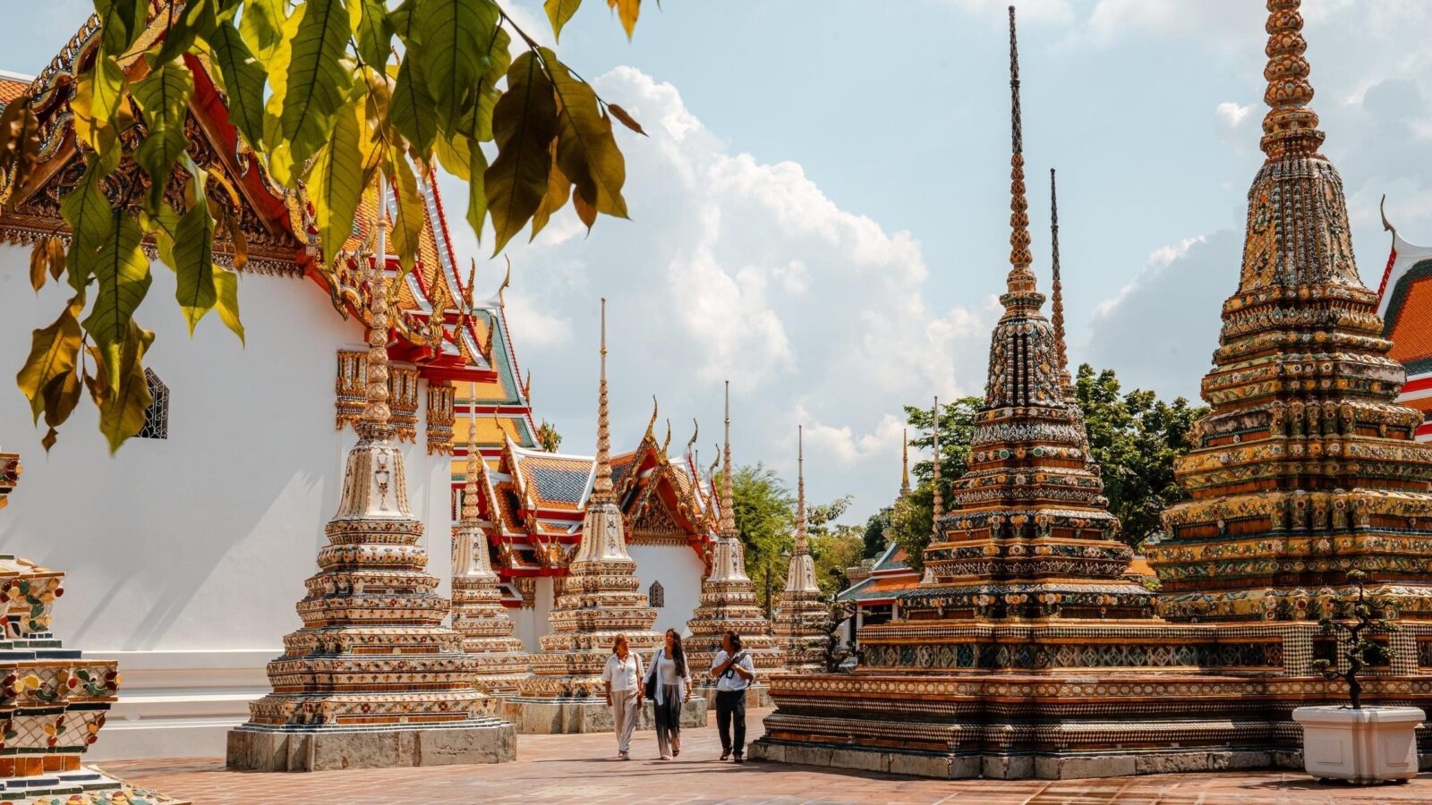 A private guided tour of Wat Pho in Bangkok, Thailand. A mother and daughter with their private guide walking among the beautiful architecture.