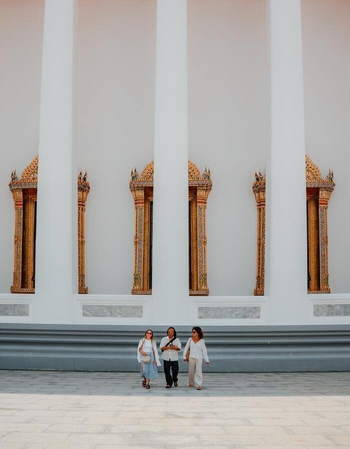 A guide walks with two guests on a Bangkok temple tour.