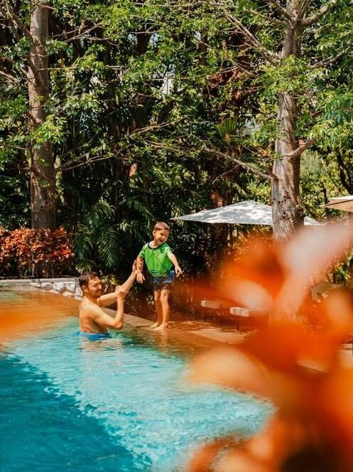 A father and son enjoy time in a swimming pool in Thailand.