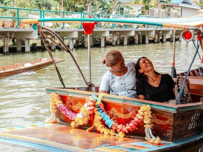 A woman and her daughter laugh at the front of a private klong boat in Bangkok.