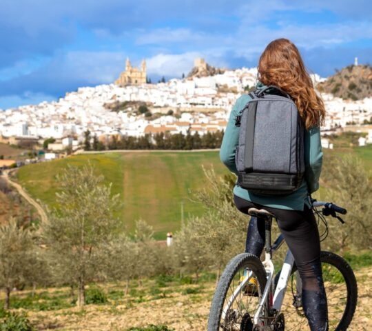 Woman on a bike looking at a panoramic view of a Spanish city landscape, a typical white house village in Olvera.