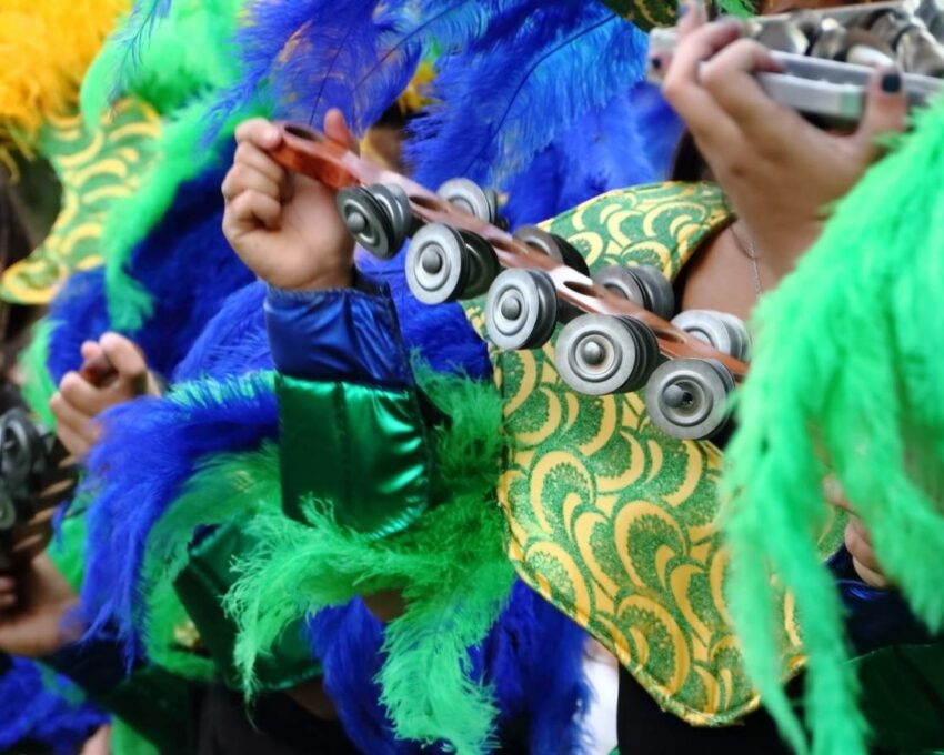 Close up of carnaval goers in Brazil wearing bright blue and green costumes and playing percussion instruments