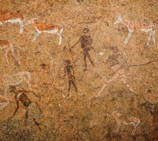 Ancient rock paintings of hunters and animals on a textured, earthy stone wall.
