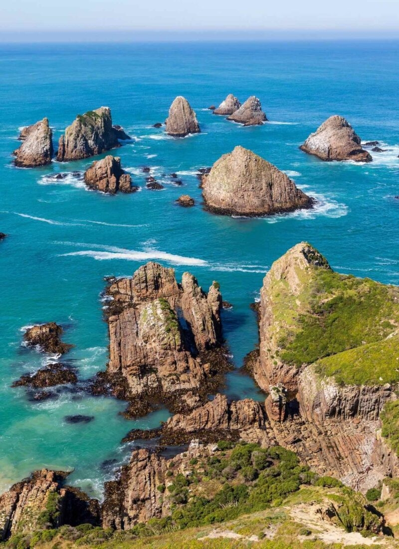 Rocky sea stacks and small islets protruding from vibrant blue and turquoise ocean water.